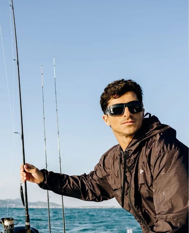 Pescador con anteojos de sol Mormaii frente al mar